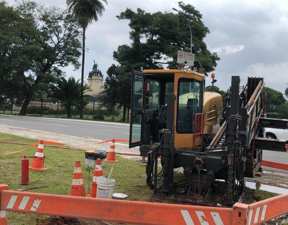Perfuratriz da DRC em canteiro cercado junto ao Monumento do Ipiranga, com a área verde preservada e a avenida em operação